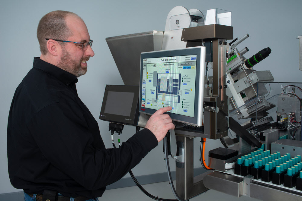 A man uses the controls screen for a lip balm filling machine.