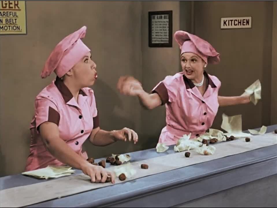 I Love Lucy image from season 2, episode 1 of Lucy and Ethel trying to keep up with wrapping chocolates on a conveyer belt.